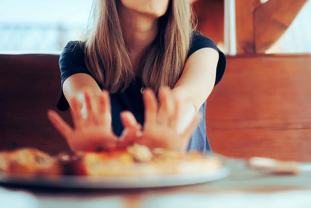 Pregnant woman looking at food with a puzzled expression